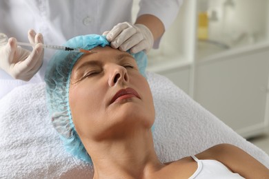 Photo of Doctor giving facial injection to senior woman in clinic. Cosmetic surgery