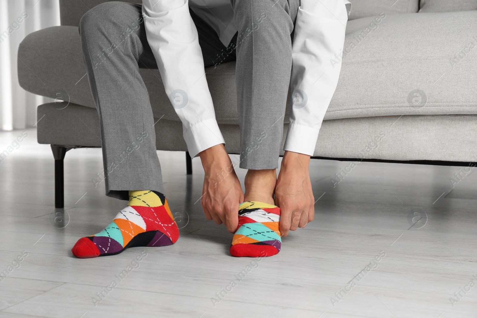 Photo of Man putting on colorful socks indoors, closeup