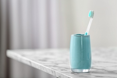 Photo of Cup with toothbrush on table. Dental care