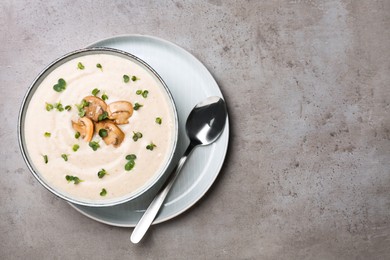 Delicious cream soup with mushrooms served on grey table, top view. Space for text