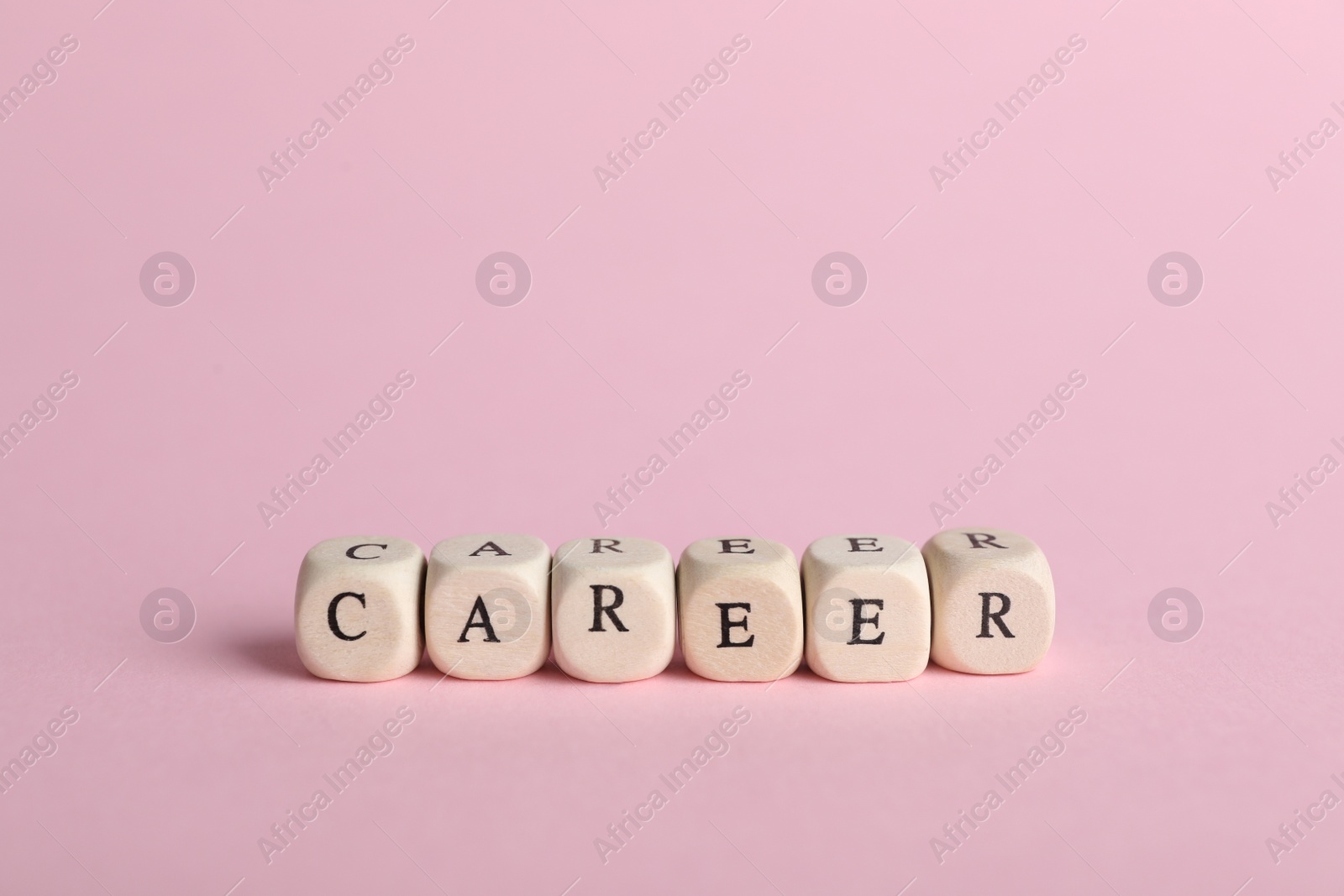 Photo of Stone cubes with word CAREER on pink background. Space for text