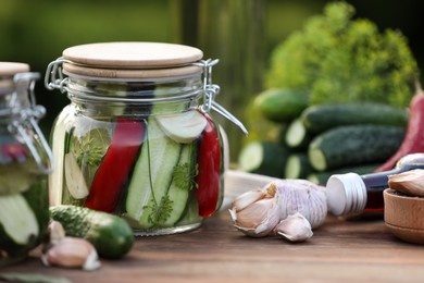 Jar of delicious pickled cucumbers on wooden table, closeup