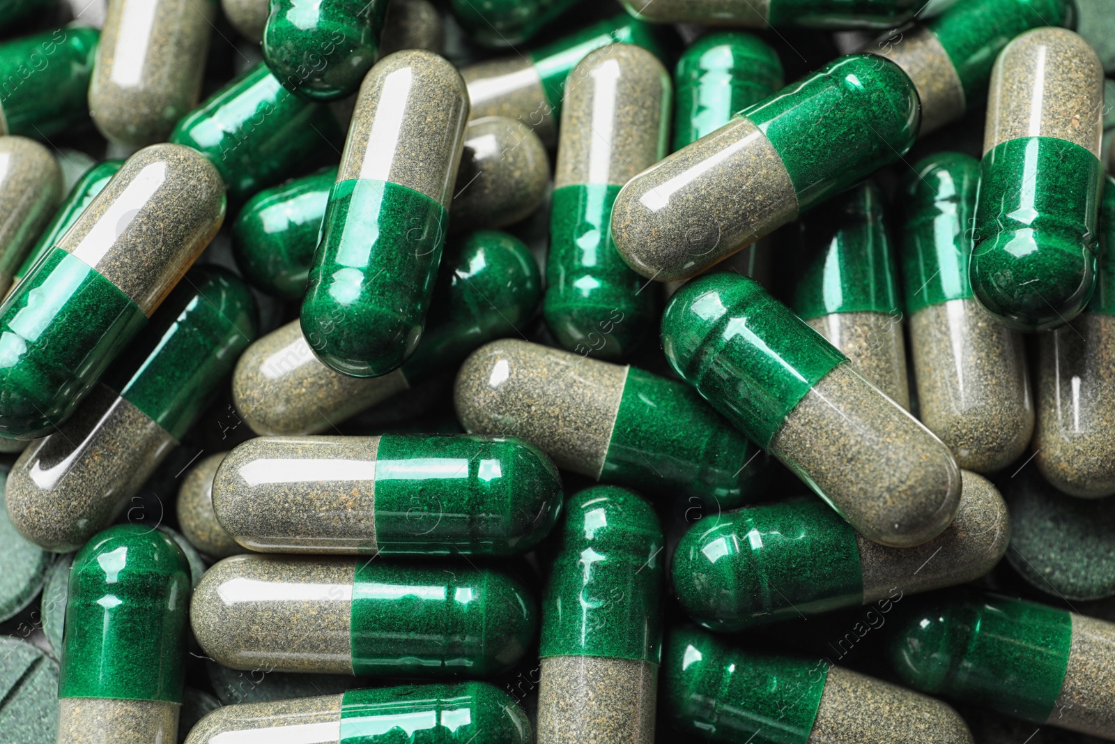 Photo of Green organic spirulina capsules as background, closeup