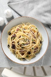 Delicious pasta with anchovies, olives and parmesan cheese served on grey marble table indoors, flat lay