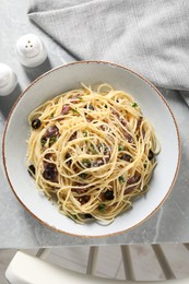 Photo of Delicious pasta with anchovies, olives and parmesan cheese served on grey marble table indoors, flat lay