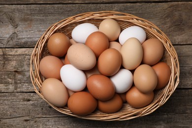Photo of Fresh chicken eggs in wicker basket on wooden table, top view