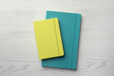 Photo of Yellow and turquoise planners on white wooden table, top view