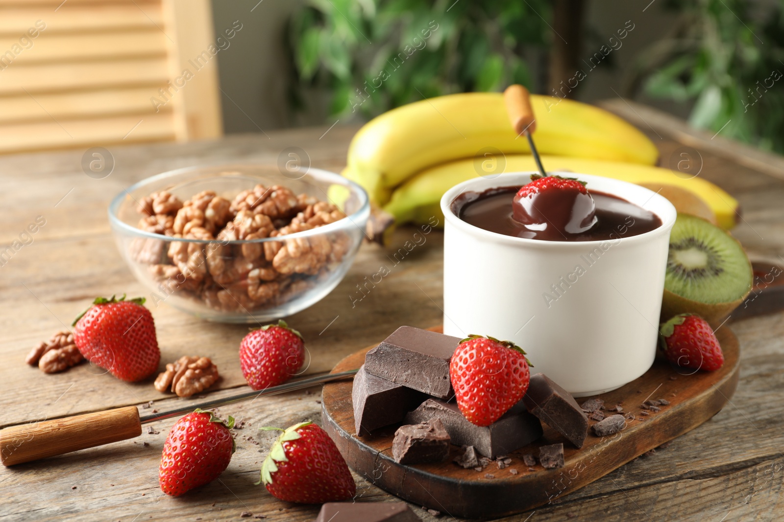 Photo of Fondue pot with chocolate and different products on wooden table