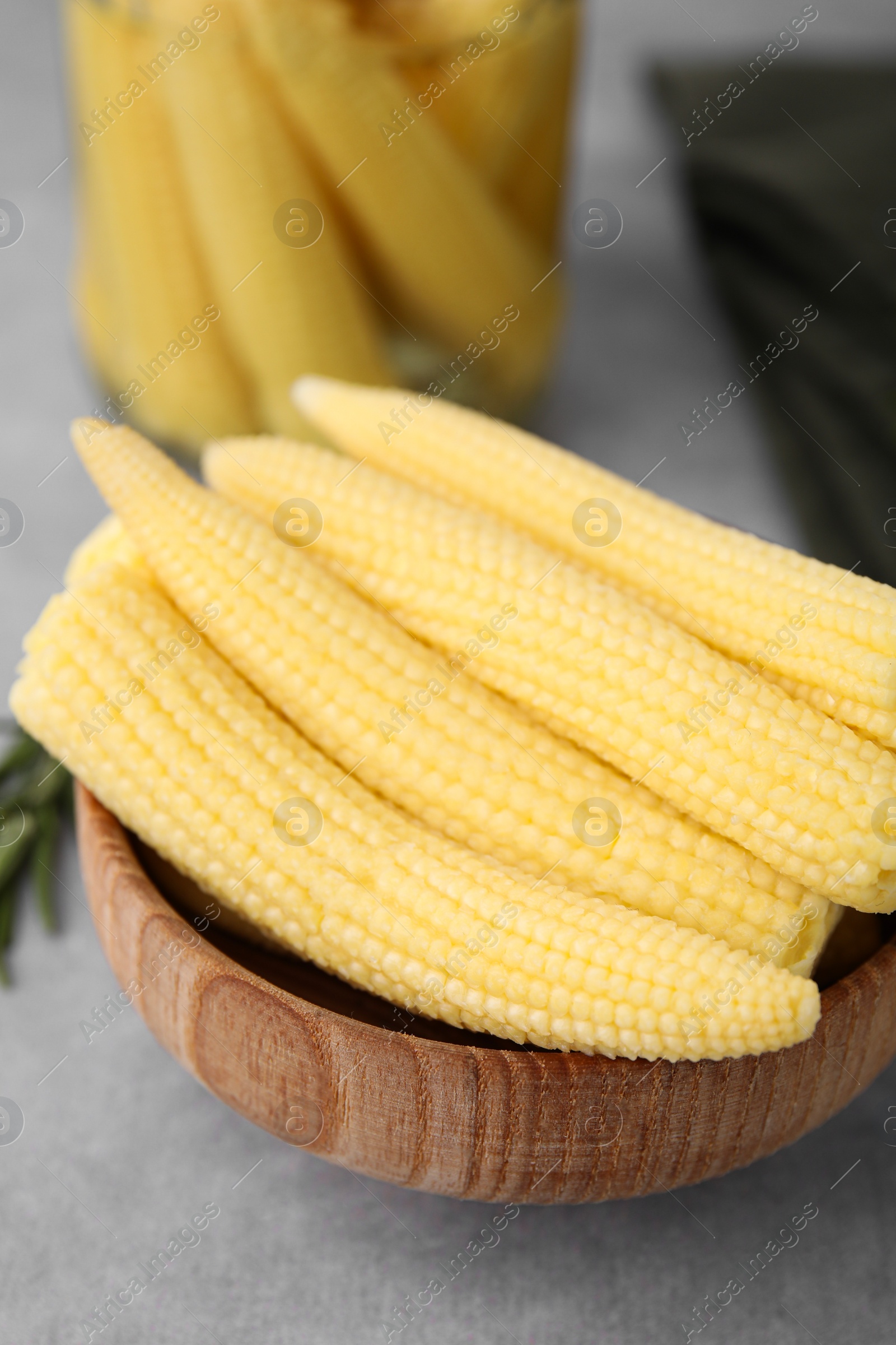 Photo of Tasty fresh yellow baby corns in bowl on grey table, closeup