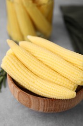 Photo of Tasty fresh yellow baby corns in bowl on grey table, closeup