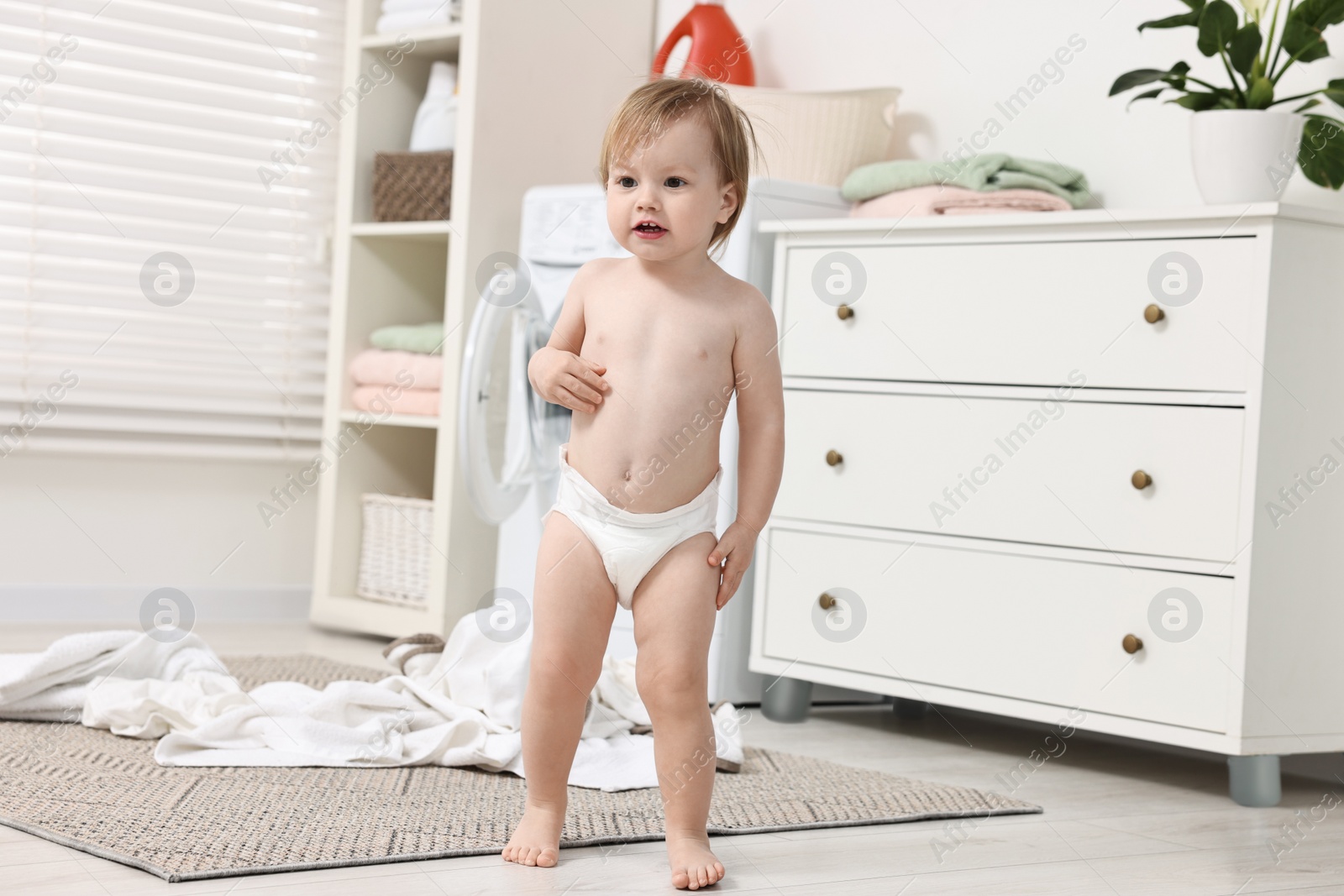 Photo of Little girl near baby clothes at home