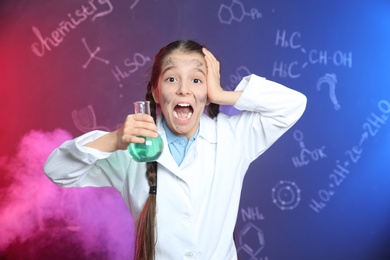 Photo of Emotional pupil holding Florence flask in smoke against blackboard with chemistry formulas