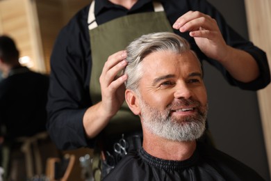 Photo of Hair styling. Professional hairdresser working with happy client in barbershop, closeup