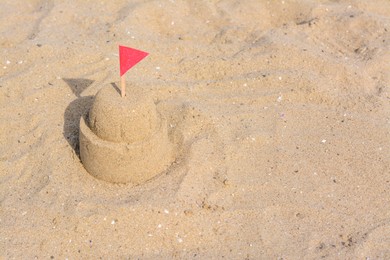 Photo of Beautiful sand castle with red flag on beach, space for text