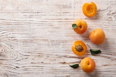 Delicious ripe apricots on white wooden background, flat lay. Space for text