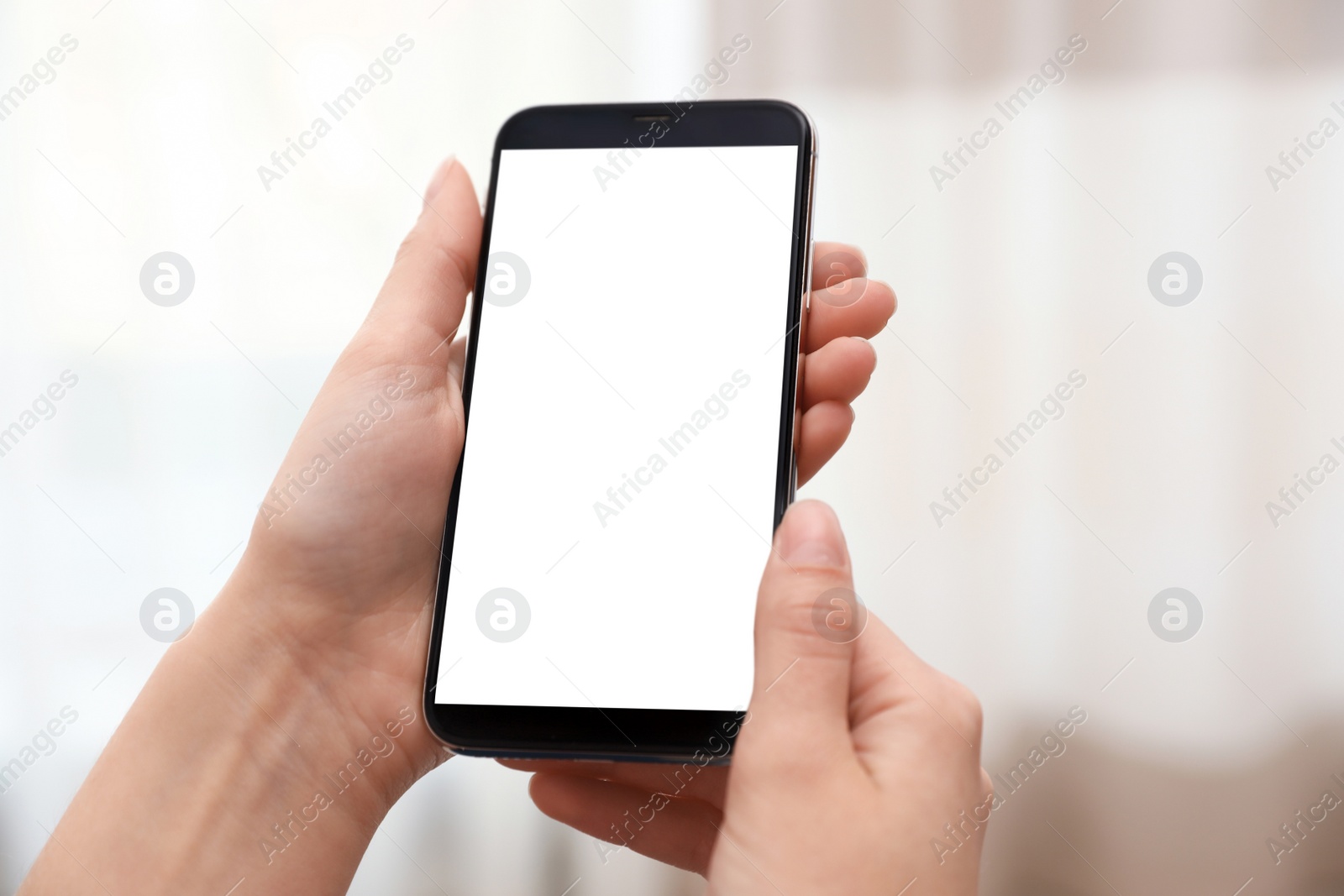 Photo of Woman holding smartphone with blank screen on blurred background, closeup of hands. Space for text
