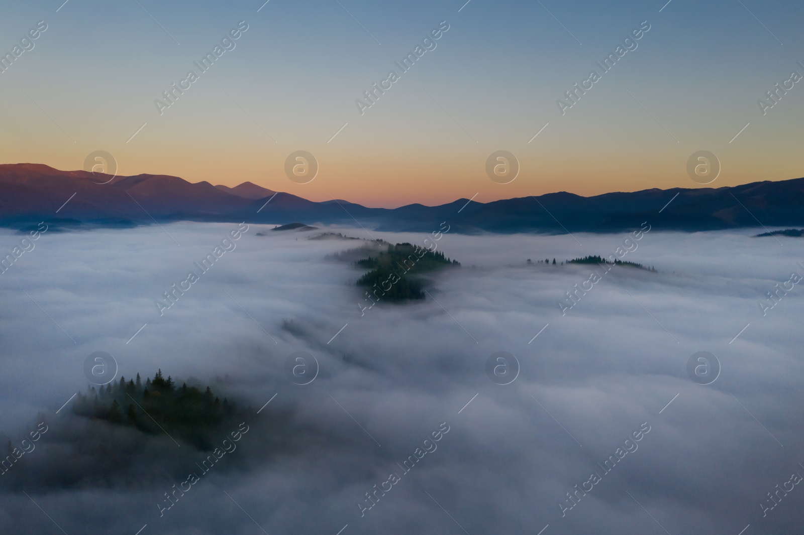 Image of Beautiful landscape with thick mist in mountains at sunset. Drone photography