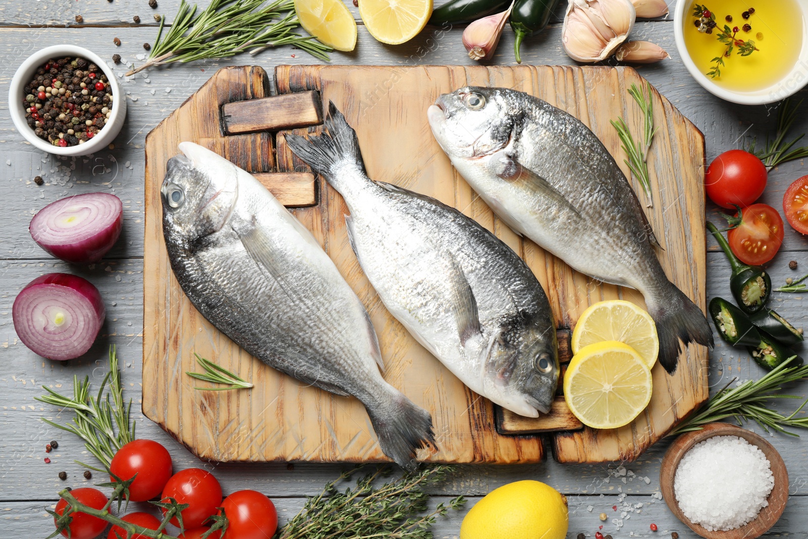 Photo of Flat lay composition with raw dorada fish on light grey wooden table