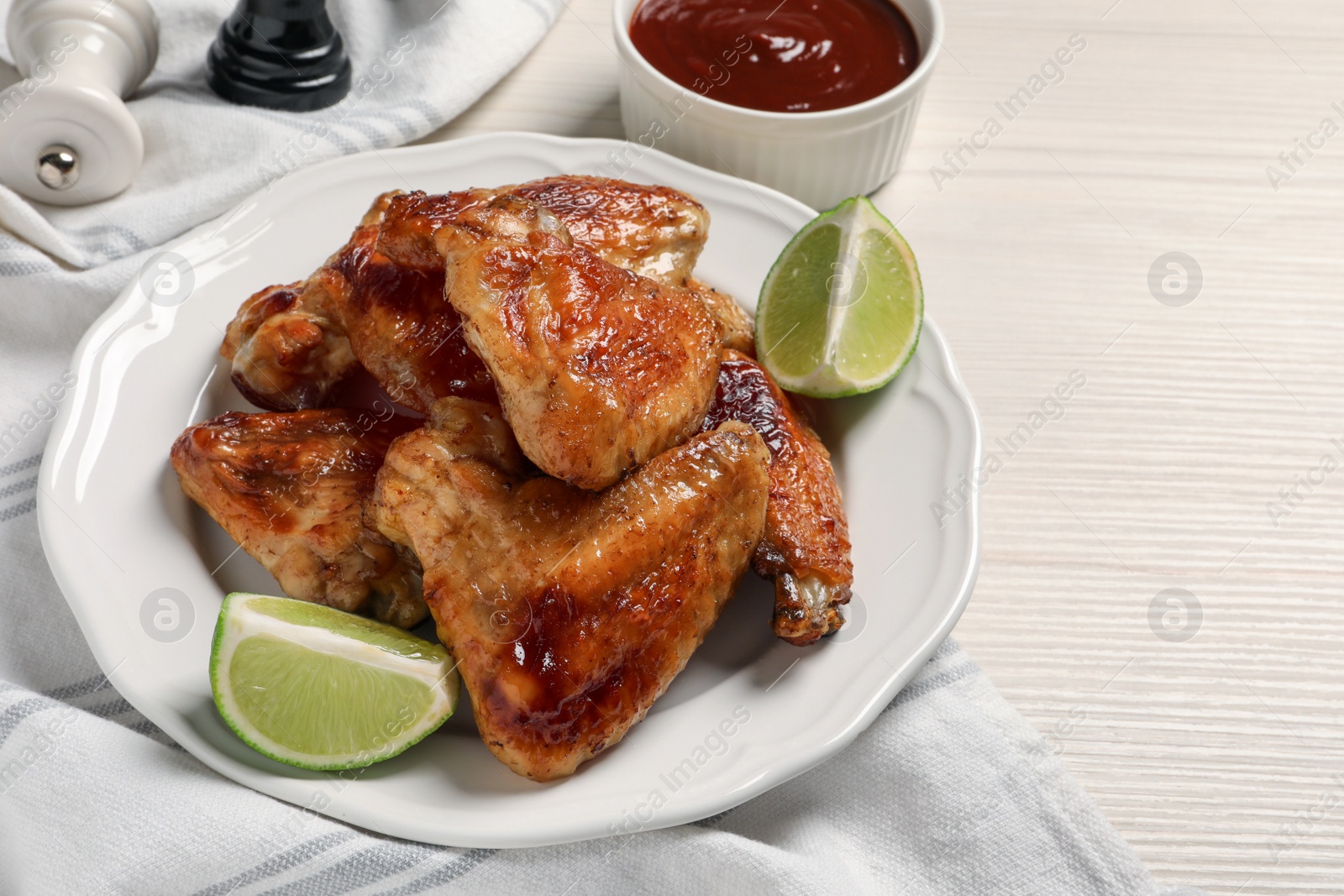 Photo of Plate with delicious fried chicken wings and lime on white wooden table