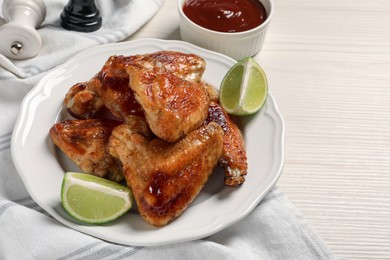 Photo of Plate with delicious fried chicken wings and lime on white wooden table