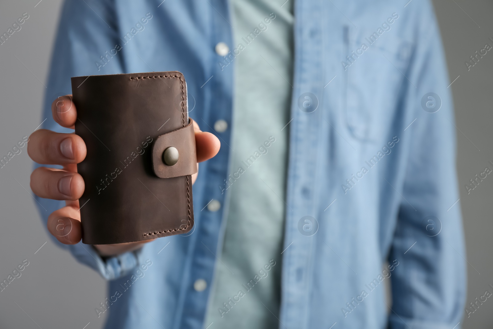 Photo of Man holding leather business card holder on grey background, closeup