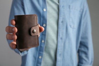 Man holding leather business card holder on grey background, closeup