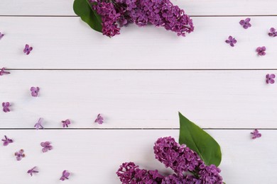 Photo of Beautiful lilac flowers on white wooden table, flat lay. Space for text