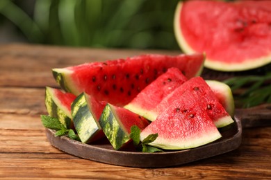Photo of Slices of delicious ripe watermelon on wooden table outdoors