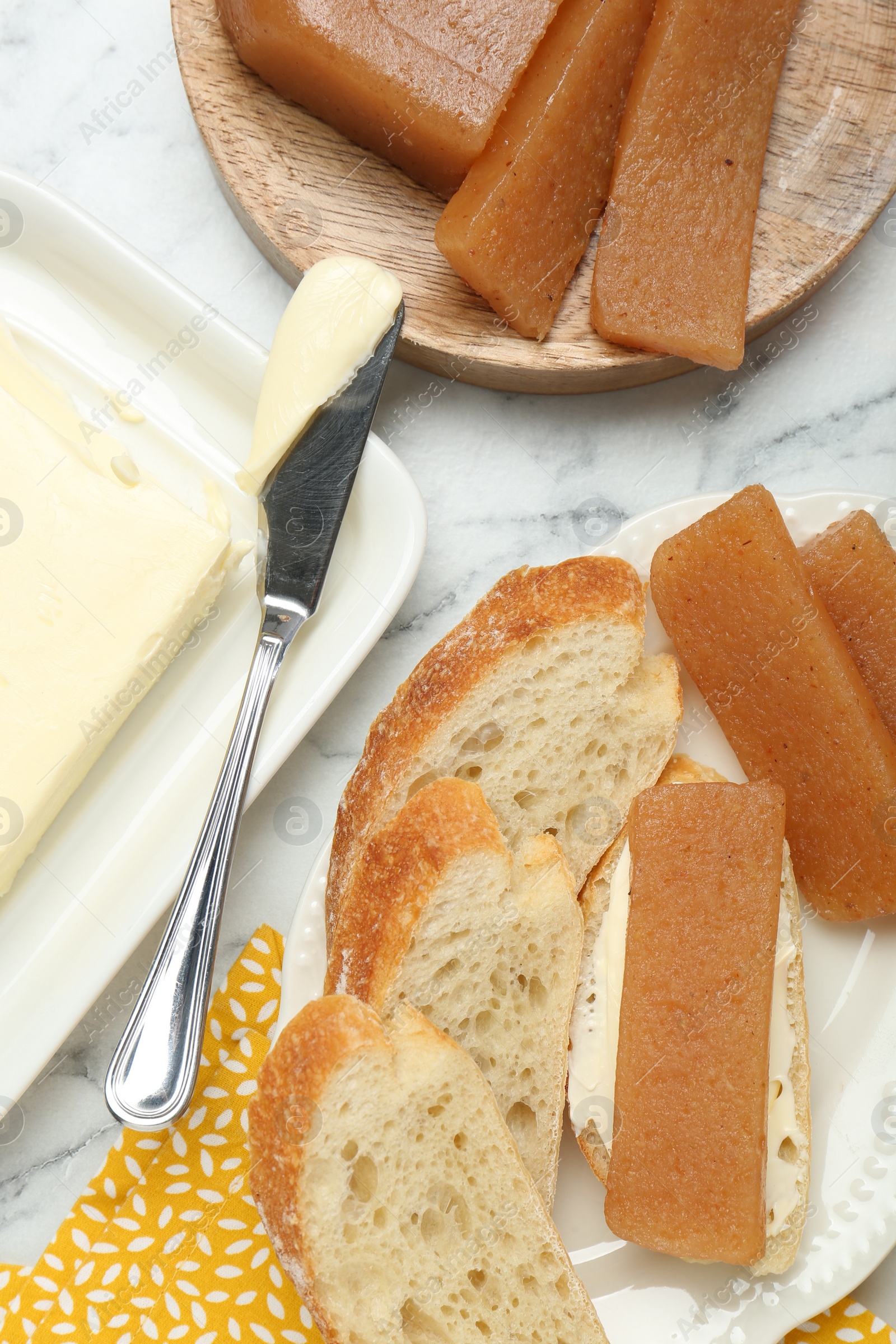 Photo of Delicious quince paste, bread and butter on white marble table, flat lay