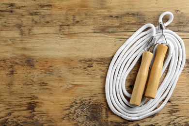 Photo of Skipping rope on wooden table, top view. Space for text