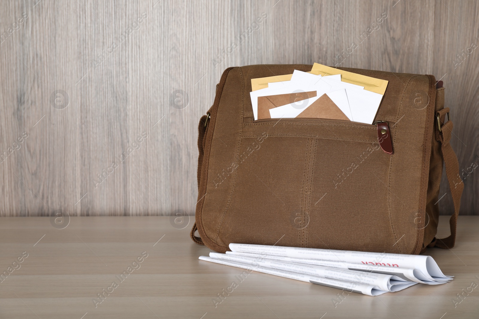 Photo of Postman's bag full with letters and newspapers on wooden background. Space for text