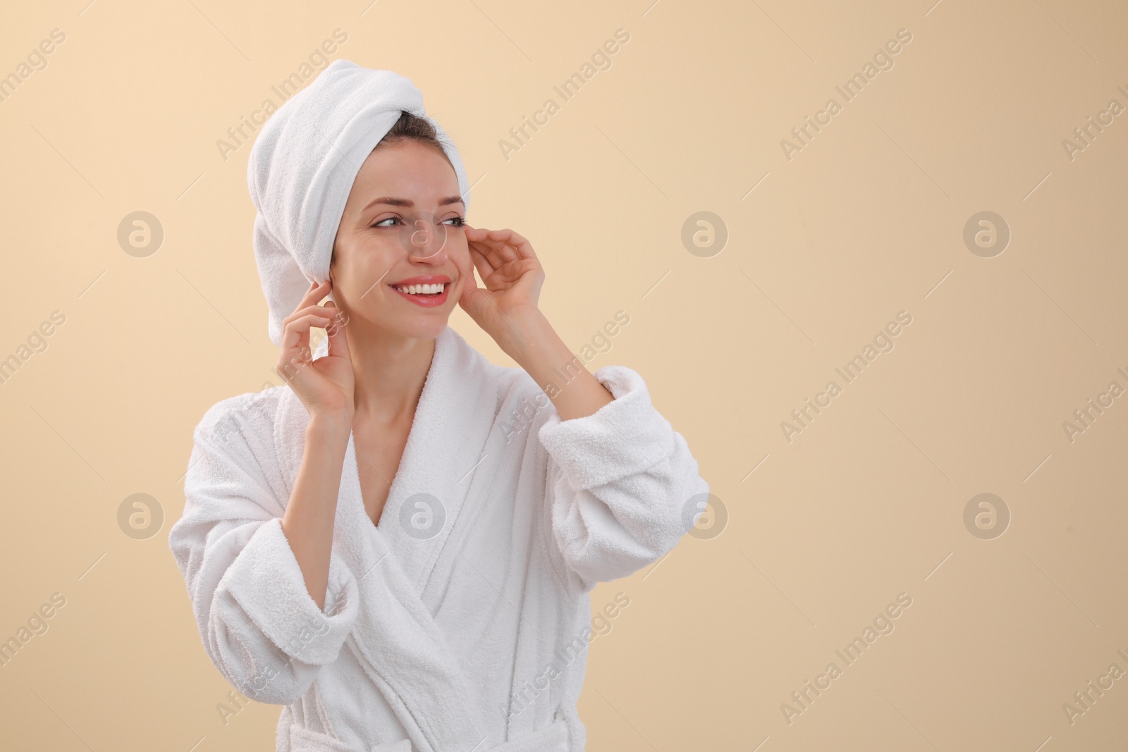 Photo of Beautiful young woman with hair wrapped in towel after washing on beige background