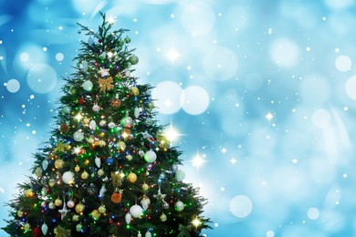 Image of Beautifully decorated Christmas tree on light blue background, space for text. Bokeh effect