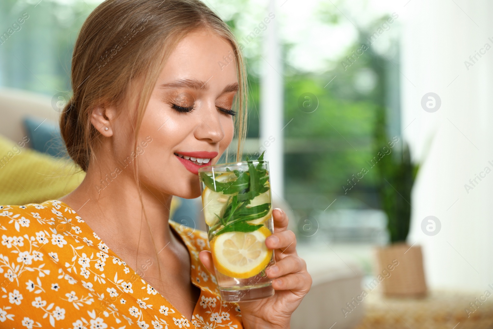 Photo of Young woman with glass of lemonade at home. Refreshing drink