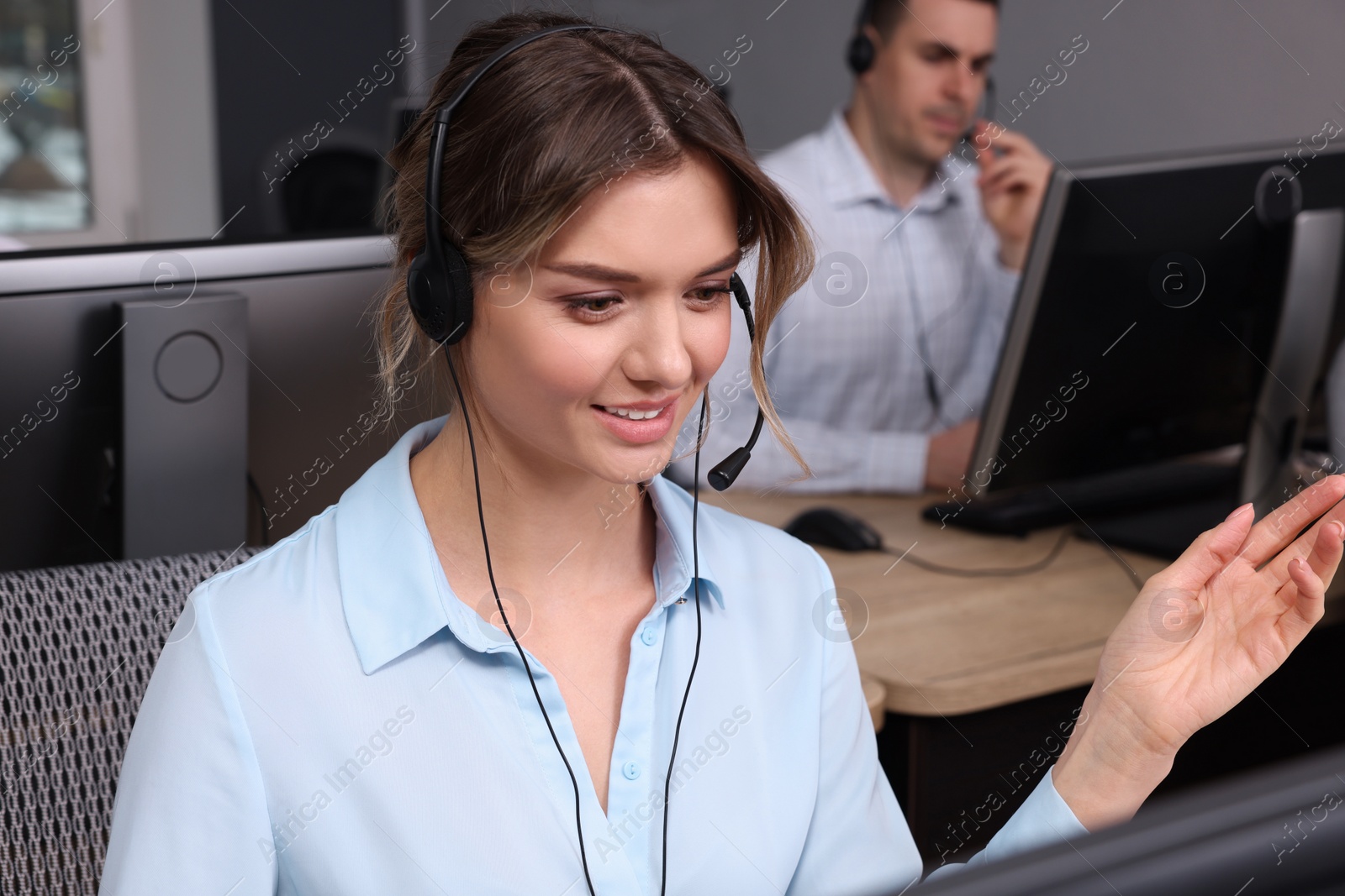 Photo of Call center operators working in modern office, focus on young woman with headset