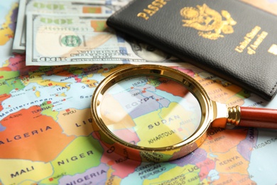 Passport, money and magnifier on world map. Travel agency