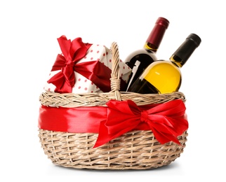 Photo of Festive basket with bottles of wine and gift on white background