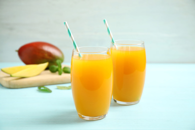 Photo of Fresh delicious mango drink on light blue wooden table