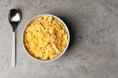Photo of Bowl with healthy cornflakes and spoon on table, top view. Space for text