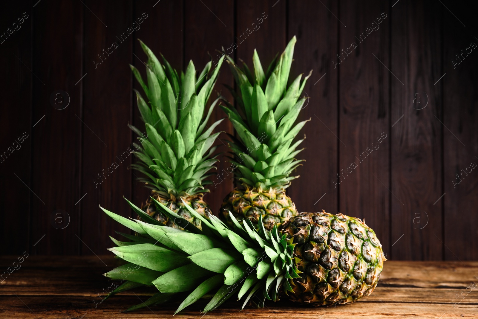 Photo of Fresh ripe juicy pineapples on wooden table