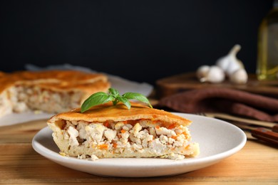 Photo of Slice of delicious meat pie with basil on wooden table, space for text