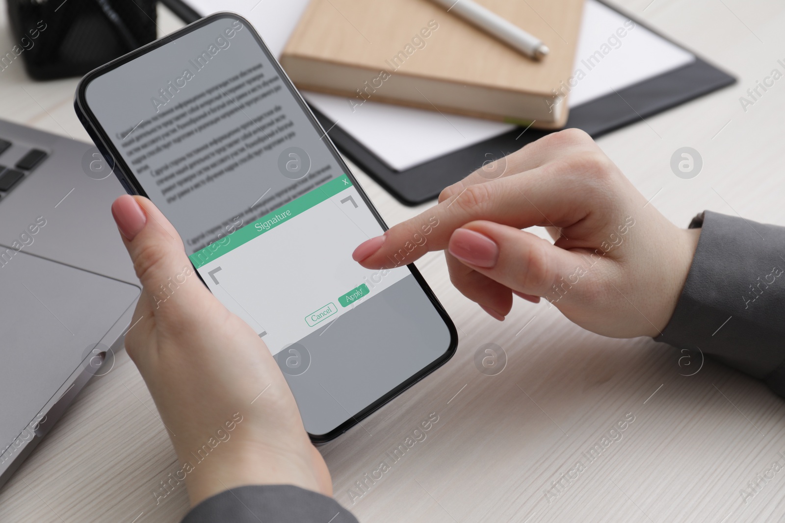 Image of Electronic signature. Woman using mobile phone at white wooden table, closeup