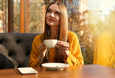 Woman listening to audiobook at table in cafe