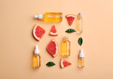 Photo of Flat lay composition with grapefruit slices and bottles of essential oil on color background