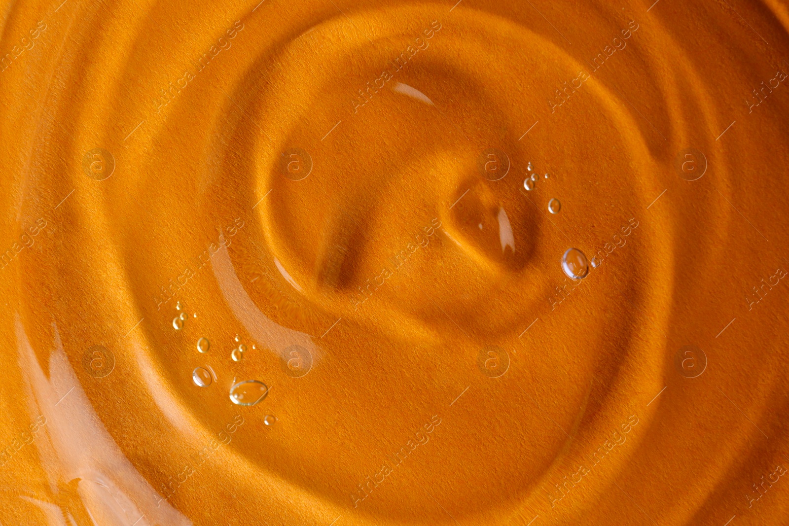 Photo of Sample of transparent shower gel on orange background, closeup