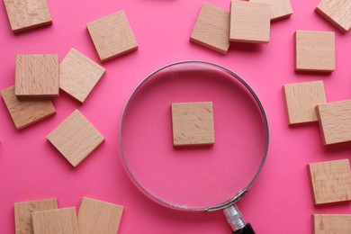 Photo of Magnifying glass and pieces of wood on pink background, flat lay