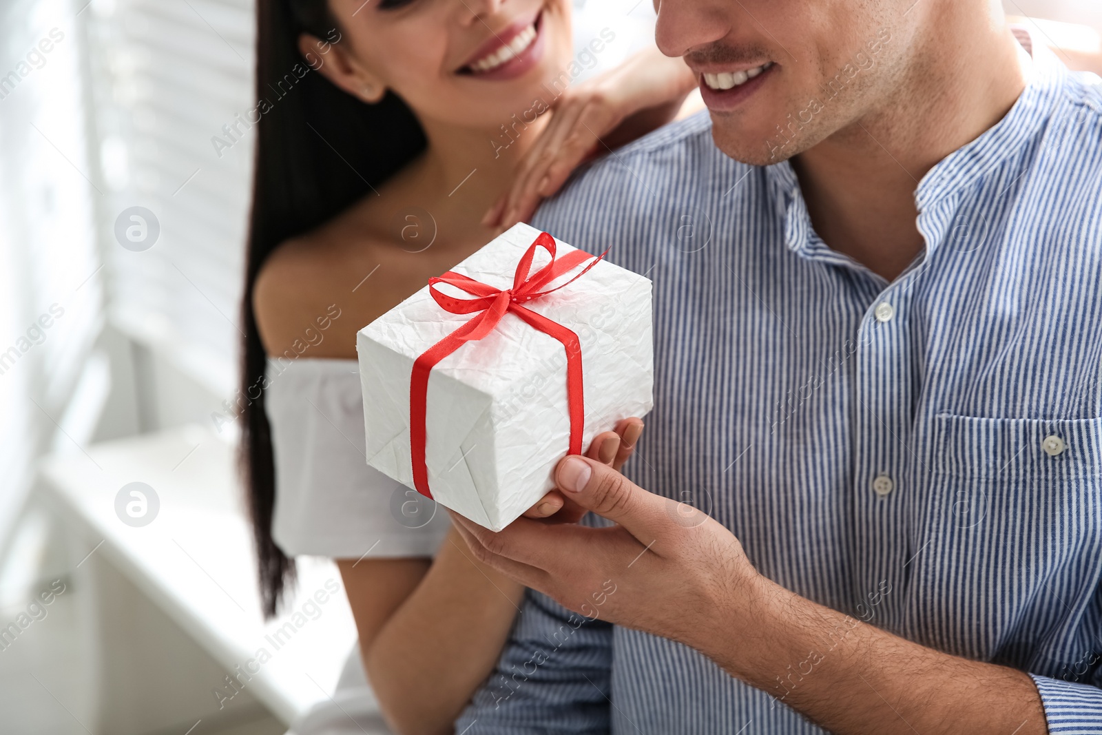 Photo of Man presenting gift to his beloved woman at home, closeup. Valentine's day celebration