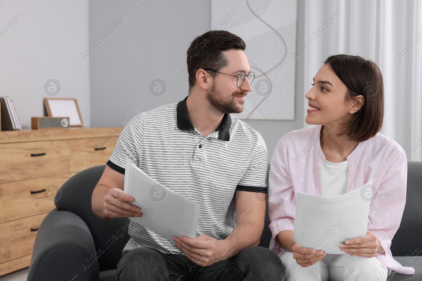 Photo of Young couple with papers discussing pension plan indoors