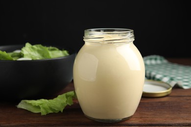 Jar of delicious mayonnaise and fresh salad on wooden table