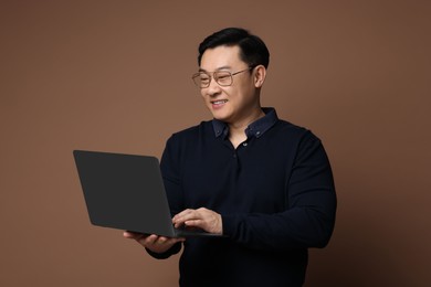 Photo of Portrait of happy man with laptop on brown background